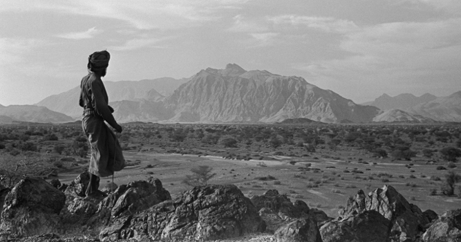 View of a member of Wilfred Thesiger's travelling party looking out across the Wadi Sayfam towards Jebel Kawr, Oman, March 30 – April 2, 1949 (b/w photo), Wilfred Patrick Thesiger, (1910-2003) / Pitt Rivers Museum, Oxford, UK